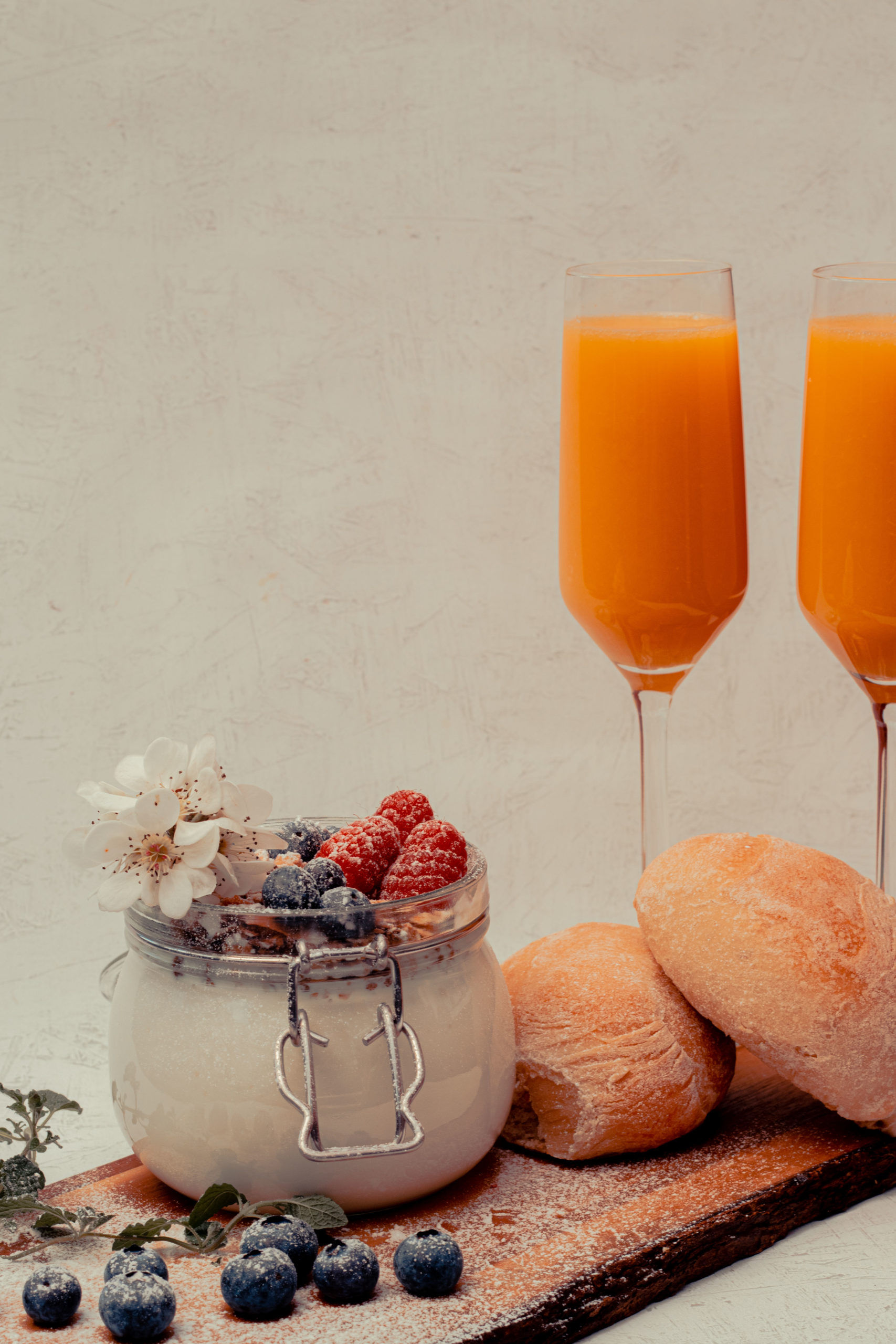 brunch, breakfast, orangejuice, buns, blueberrys, raspberrys, bowl with yoghurt and musli on a platter, mimosas